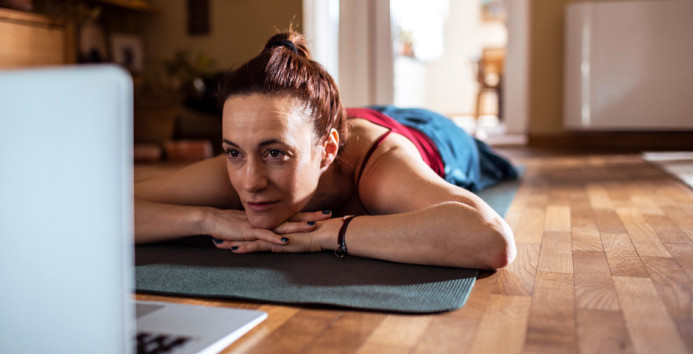 relaxing on a yoga mat while checking laptop 943x481