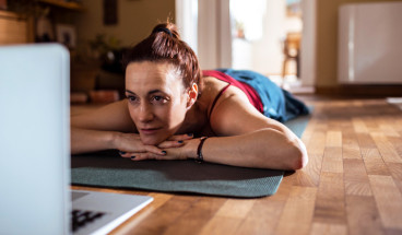 relaxing on a yoga mat while checking laptop 767x418