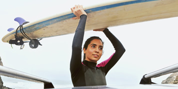 Person holding a surfboard above their head to carry it towards the sea