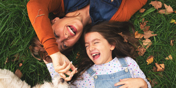 Mother and daughter having fun while lying on grass